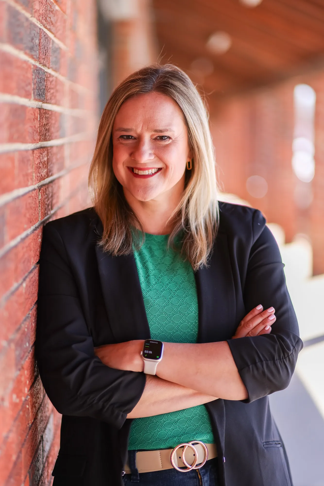 Katie Gerwel, LPC, NCC, PMH-C, smiling with arms crossed against a brick wall