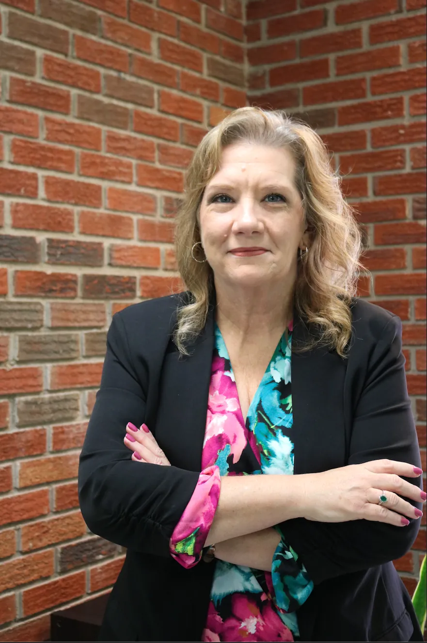 Dr. Kimberly Dolan standing with arms crossed in front of a brick wall
